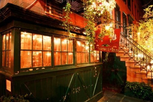 exterior restaurant view, green front, dimly lit windows with green hanging plants with side steps to entrance, Waverly Inn NYC