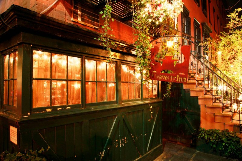 exterior restaurant view, green front, dimly lit windows with green hanging plants with side steps to entrance, Waverly Inn NYC