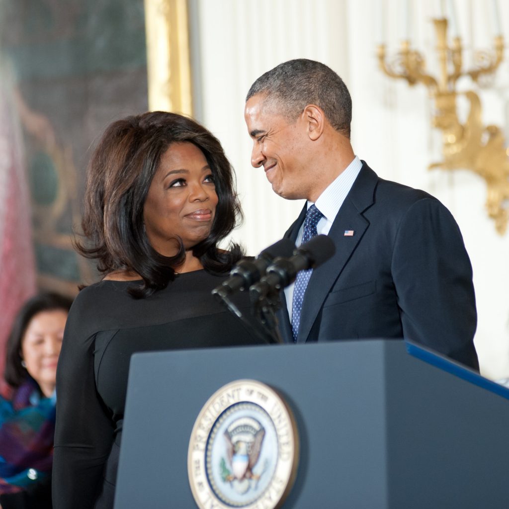 Oprah standing next to Obama at a podium. 